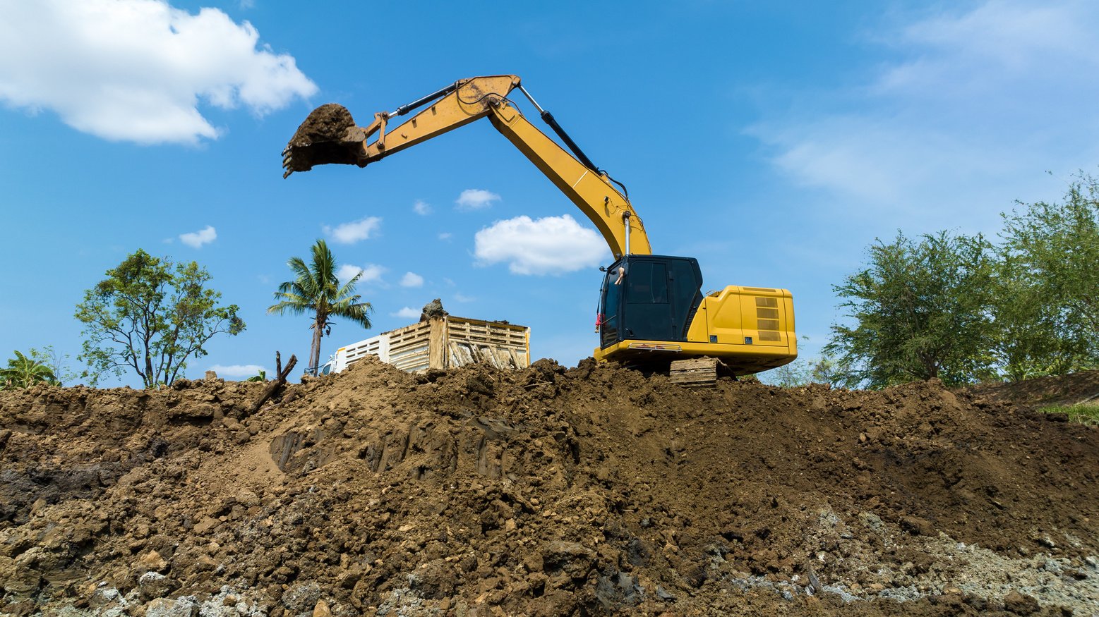 excavating soil into a dump truck to build a pond for store water for use in the dry season for agriculture